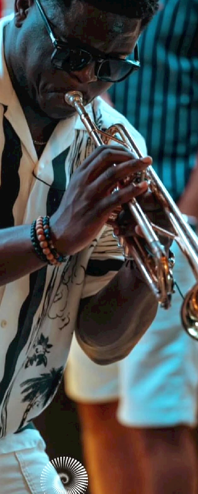 Afro-trumpetist performing under blue stage light