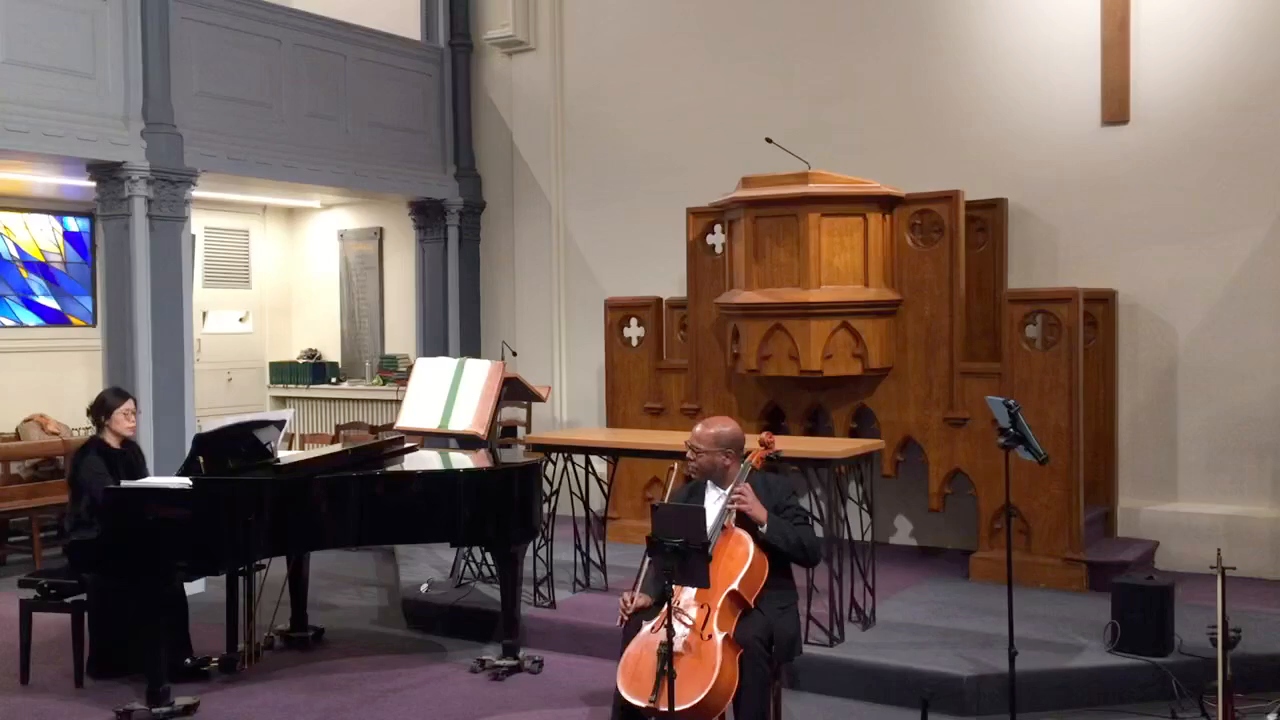 Film still of the cellist performing with a pianist