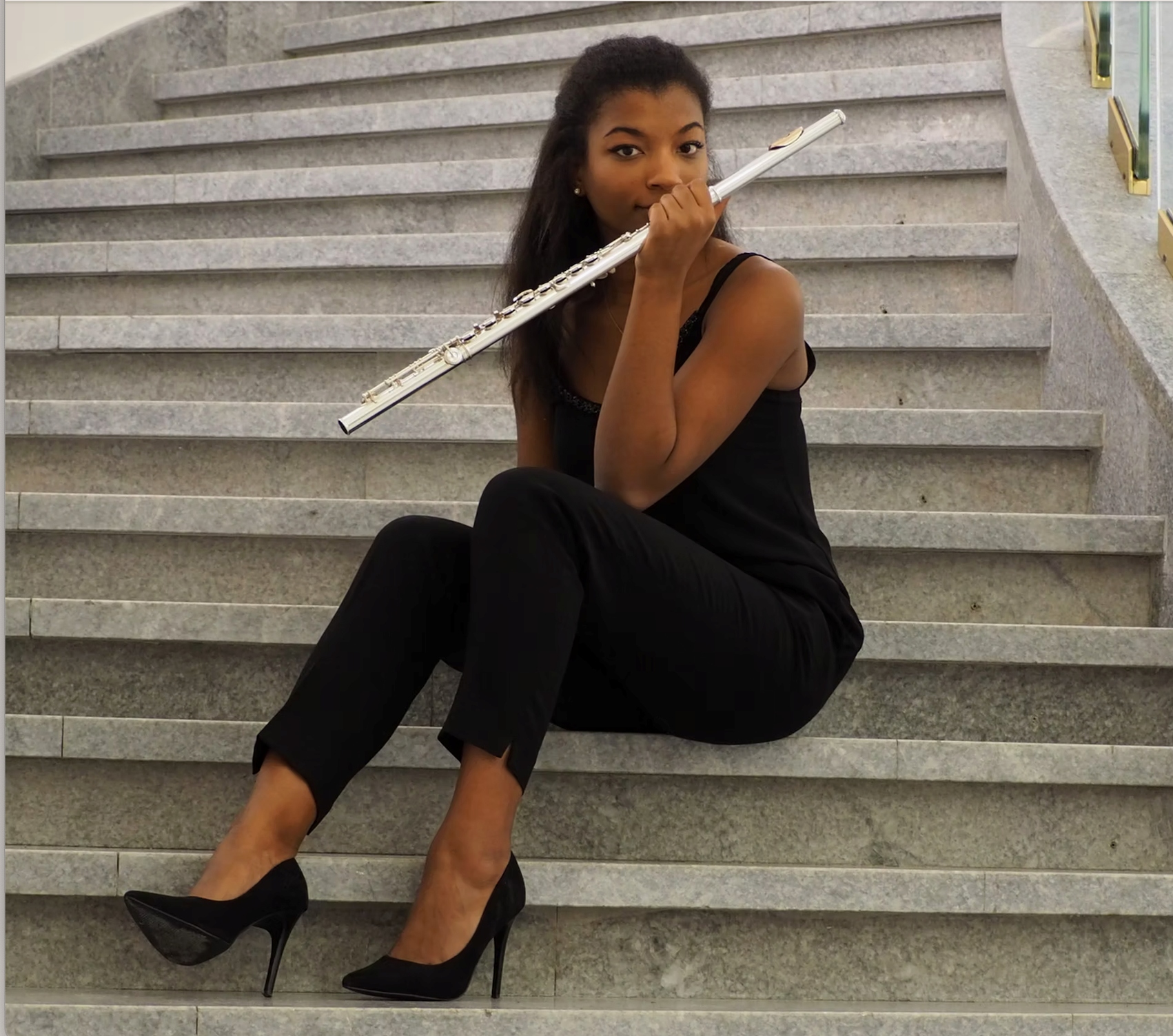 Flutist seated on stone steps with her instrument